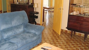 A living room with a blue sofa, a wooden cabinet with glass doors, and a dining area in the background. - Vacation home on the dune, directly on the beach, simple but ideal for the vacations (Hourtin)