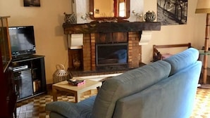 A living room with a sofa, fireplace, television, and checkered floor. - Vacation home on the dune, directly on the beach, simple but ideal for the vacations (Hourtin)
