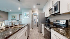 A modern kitchen with white cabinets, granite countertops, stainless steel appliances, and a central island. - Golf Cart Included, First Floor, Near Marina, Pet Friendly (Port Aransas)