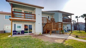 A two-story residential building with a balcony and a covered patio area. - Golf Cart Included, First Floor, Near Marina, Pet Friendly (Port Aransas)