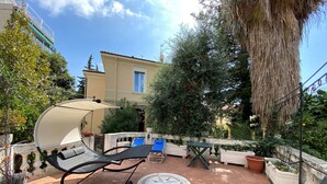 Eine Terrasse mit Liegestuhl, einem kleinen Tisch und Topfpflanzen.