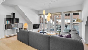 Una sala de estar moderna con un sofá gris, un televisor de pantalla plana y una estantería.