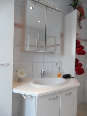 Un bagno con lavandino bianco, specchio e porta asciugamani.