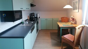 A compact kitchen with a microwave, coffee maker, and a dining area with a table and chairs.