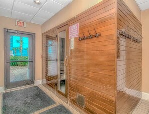 An indoor entrance with an exit sign, a notice board, and a coat rack.