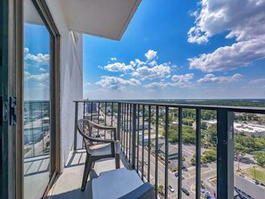 A balcony with a chair, a view of a cityscape, and a clear sky. - Coastal Luxe | Palace Twenty-One Thirteen (Myrtle Beach)