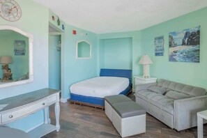 Una habitación con cama, cómoda, espejo, mesita de noche, sofá y un cuadro.