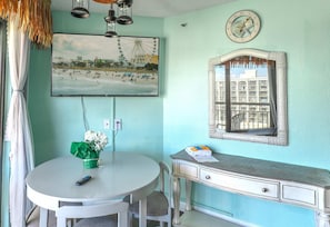 Una habitación con una mesa redonda, una silla, un reloj de pared, un cuadro enmarcado y un aparador.