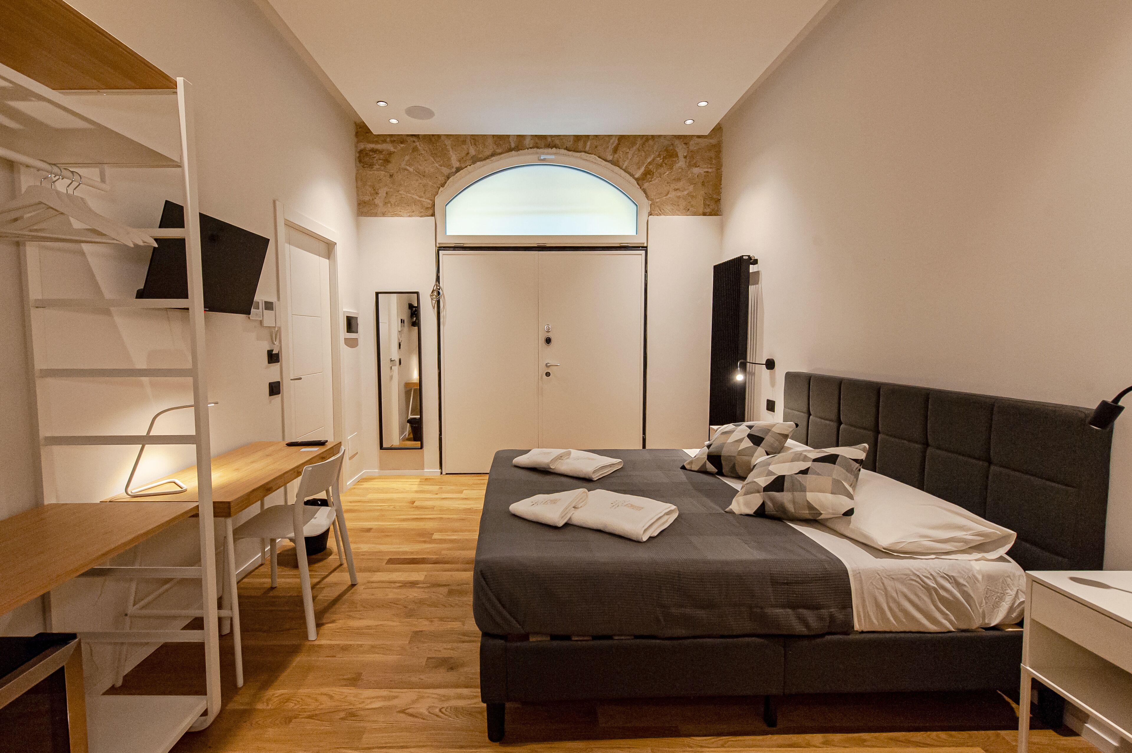 A bedroom with a bed, a desk, and a wardrobe.