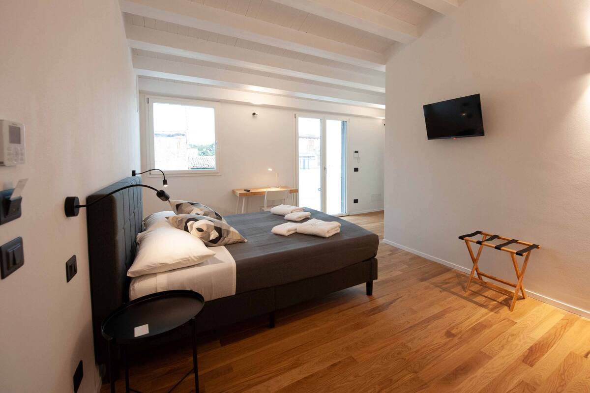 Een moderne slaapkamer met een bed, nachtkastje en een aan de muur bevestigde televisie.