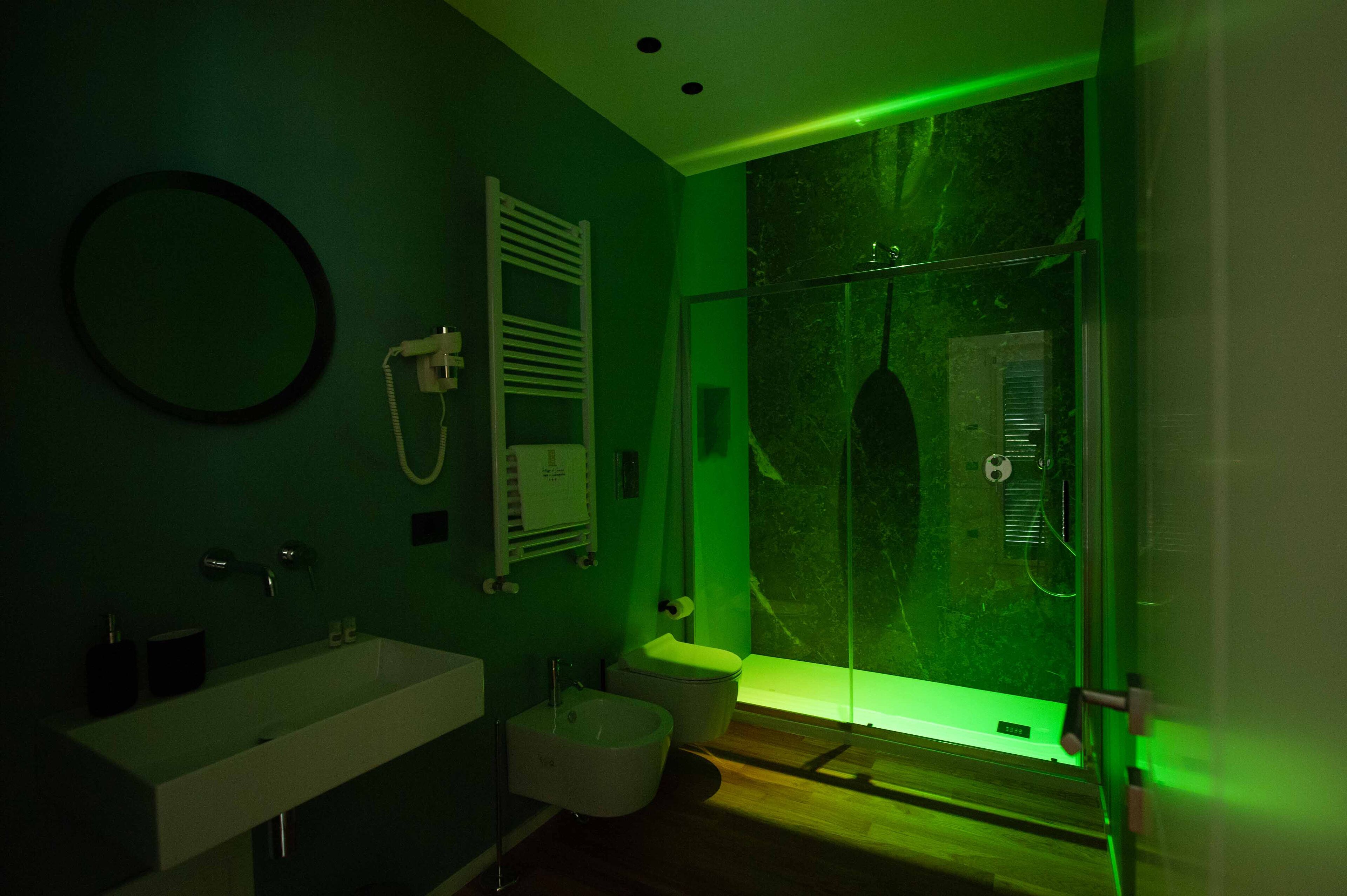 A modern bathroom with a large mirror, a sink, a toilet, and a glass shower enclosure.