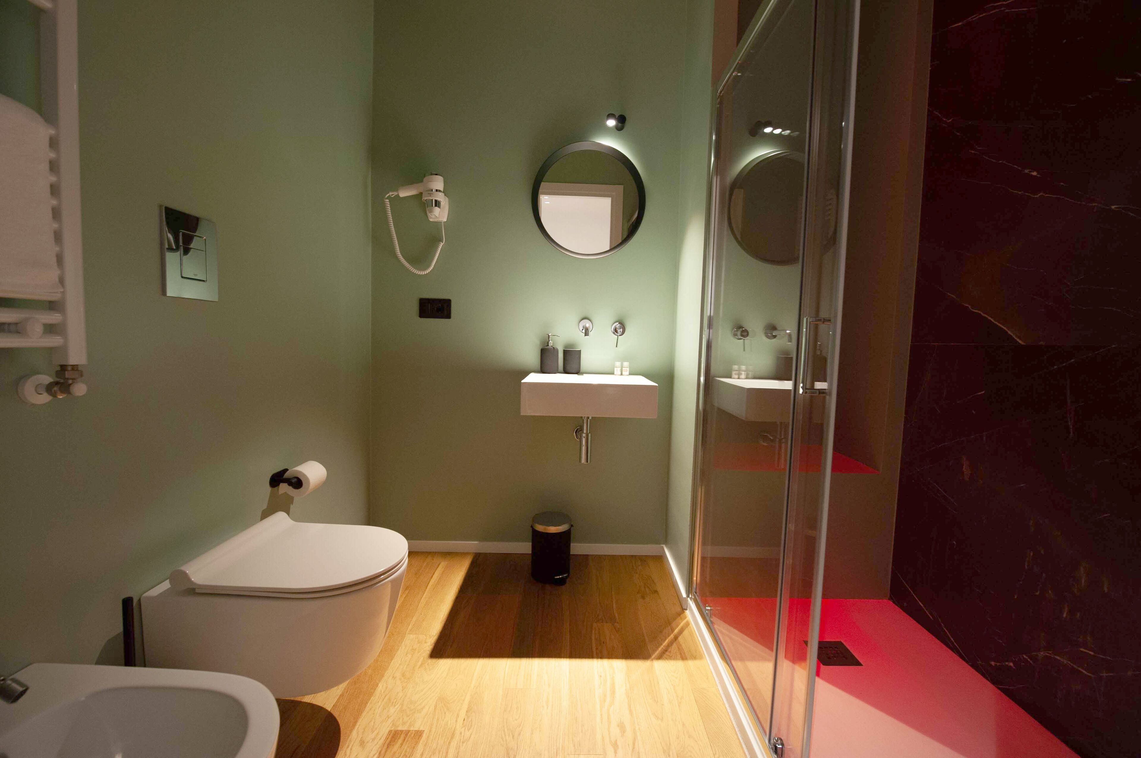 A modern bathroom with a toilet, bidet, sink, and a glass shower enclosure.