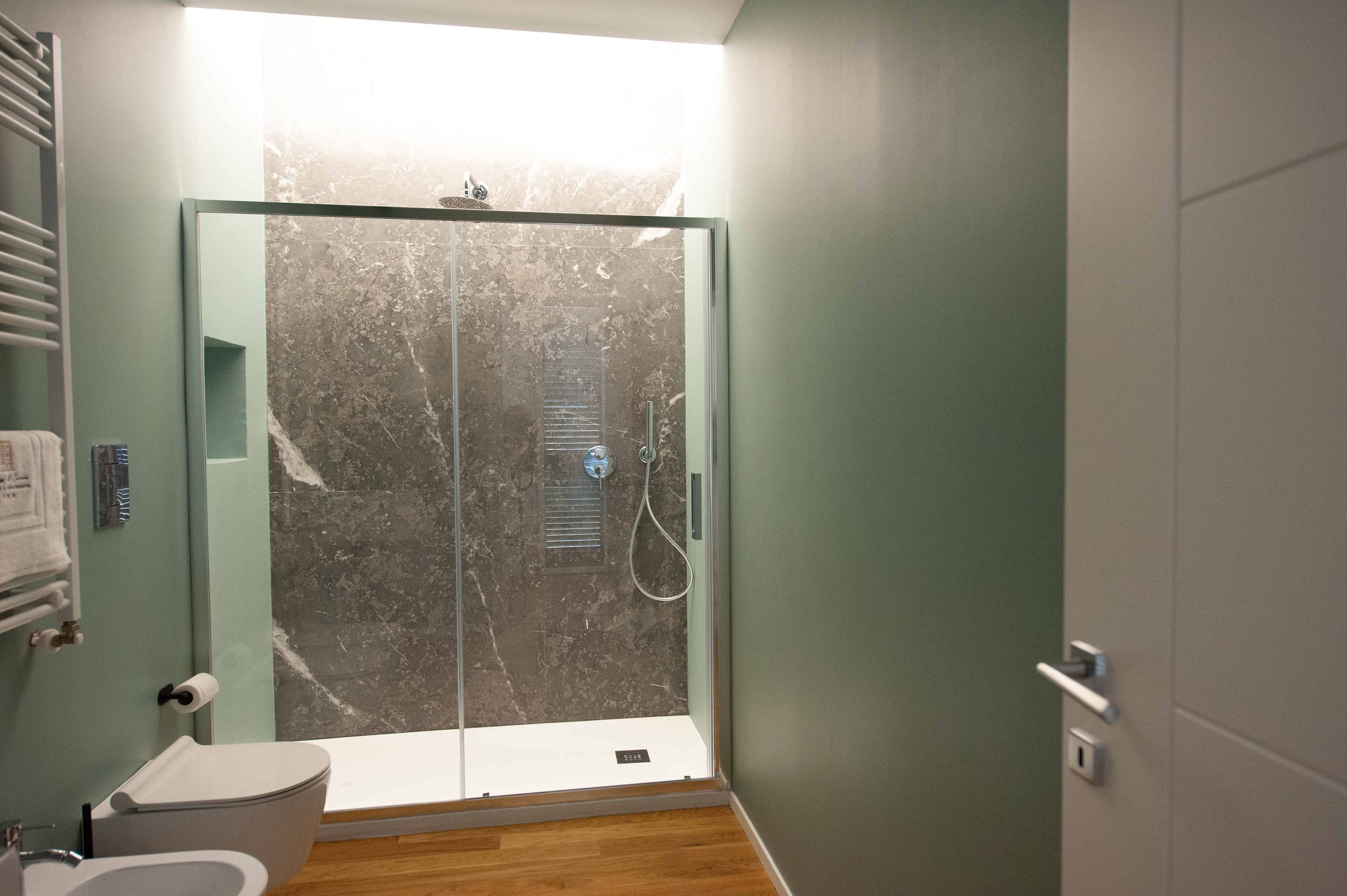 A modern bathroom with a glass-enclosed shower, a toilet, and a sink.