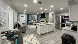 Una cocina moderna con una isla central, electrodomésticos de acero inoxidable y una zona de comedor con una mesa dispuesta para cuatro.