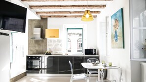 Une cuisine moderne avec un coin repas, comprenant un téléviseur, une cuisinière et une table à manger avec des chaises.