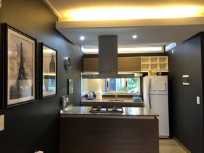 Een moderne keuken met een centraal eiland, inbouwapparatuur en kunstwerken in lijsten aan de wanden.