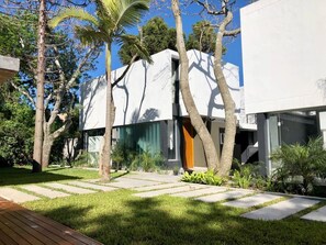 Een modern gebouw met een plat dak, omgeven door een verzorgd gazon en bomen.