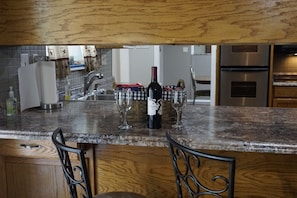 A kitchen with a granite countertop, wine bottle, and glasses. - Spacious home with Billiard Poker Ping Pong tables,Hot Tub & More on Lake Texoma (Kingston)