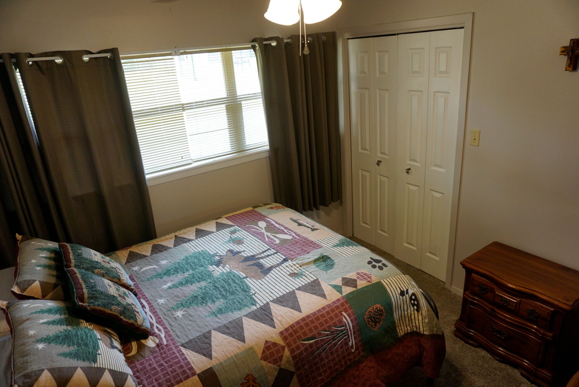 Quarto com cama, penteadeira, guarda-roupa e janela com cortinas.