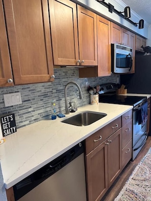 A kitchen with wooden cabinets, a stainless steel sink, a microwave, and a dishwasher.