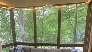 A covered outdoor seating area with a cushioned sofa and a glass-top coffee table. - Masthope  Community Charming Chalet 3 day min stay.  (Lackawaxen)