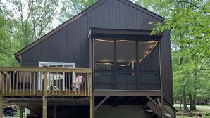 A two-story cabin with a deck and a covered garage. - Masthope  Community Charming Chalet 3 day min stay.  (Lackawaxen)