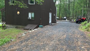 A two-story cabin with a gravel driveway, surrounded by trees. - Masthope  Community Charming Chalet 3 day min stay.  (Lackawaxen)