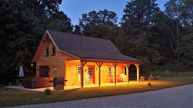 Une cabane en bois avec un porche, un barbecue et un espace salon abrité.