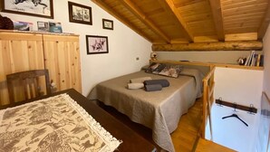 A cozy bedroom with a wooden ceiling, a bed with a grey bedspread, a wooden dresser, and a whiteboard with a hanger. - COTTAGE IN FORMER BARN WATERFALL VIEW (Piuro)