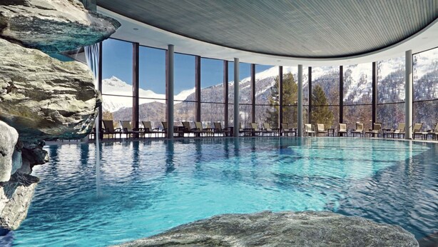 A pool with clear blue water, surrounded by large windows offering mountain views. - COTTAGE IN FORMER BARN WATERFALL VIEW (Piuro)