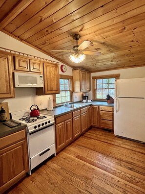 A kitchen with wooden cabinets, a stove, a microwave, and a refrigerator.