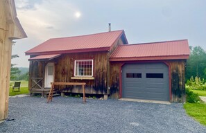 A wooden cabin with a red roof, a front door, and a garage.