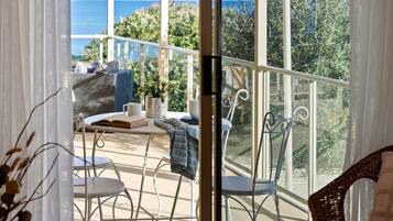 A balcony with a table, chairs, and a view of the sea.