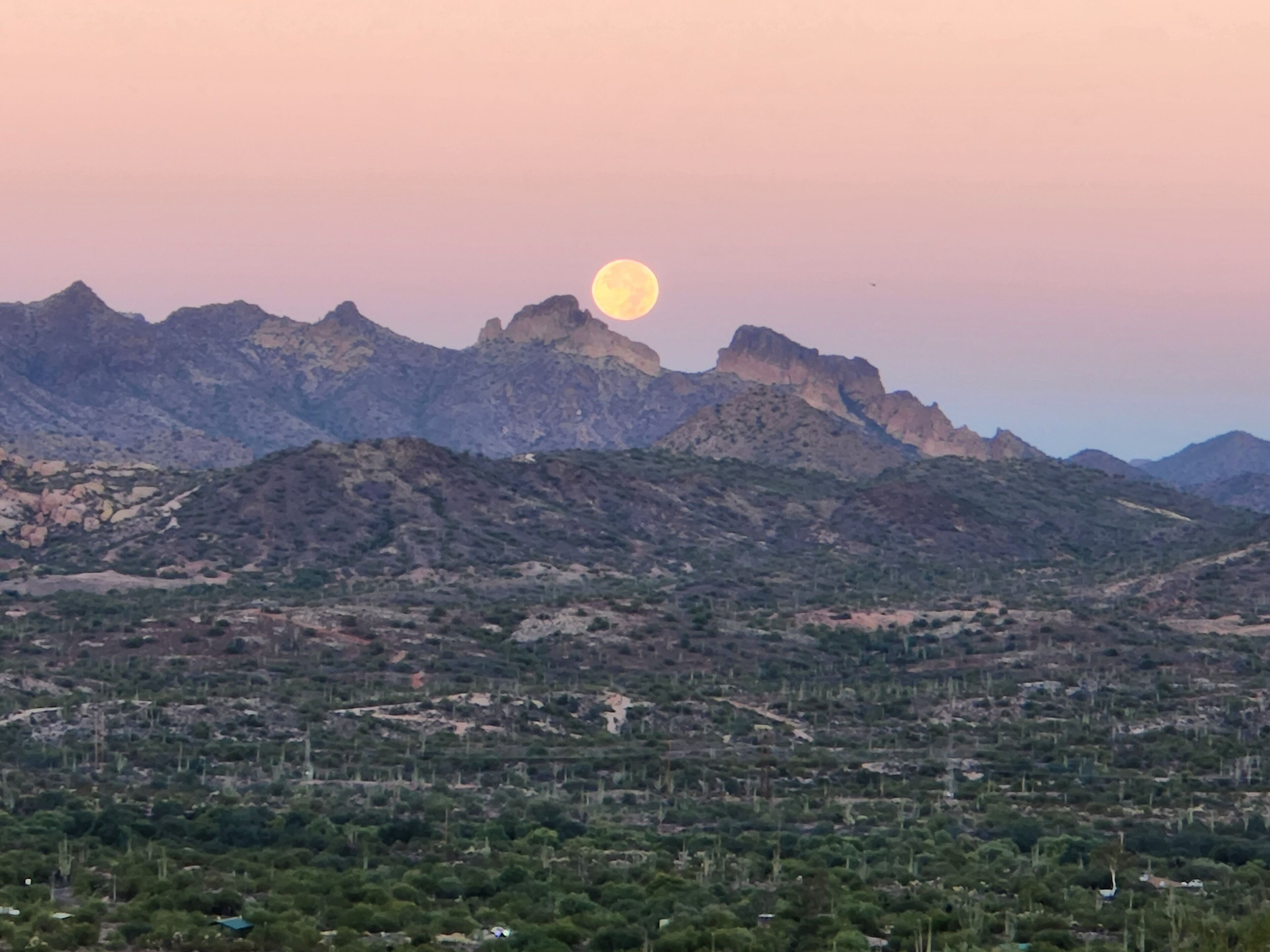 Eine Berglandschaft mit einem deutlich sichtbaren Mond am Himmel.