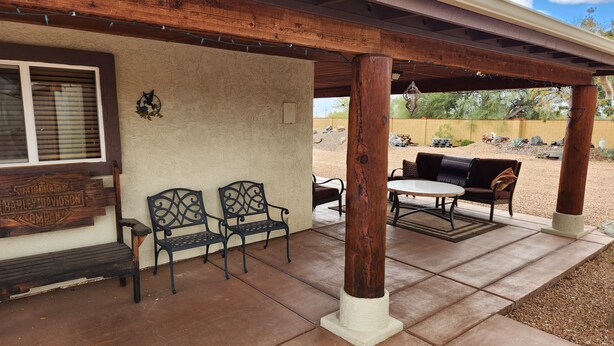 A covered patio area with two metal chairs, a table, and a bench. - Beautiful Gated Retreat with Breathtaking Views of the Superstition Mountains (Apache Junction)