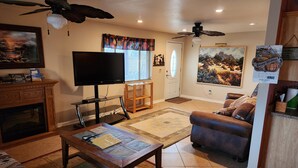 A living room with a TV, fireplace, and a ceiling fan. - Beautiful Gated Retreat with Breathtaking Views of the Superstition Mountains (Apache Junction)