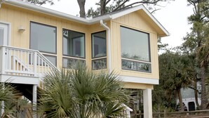 Une maison jaune avec un balcon, de grandes fenêtres et un palmier au premier plan.