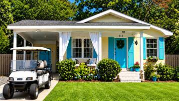 A single-story house with a covered porch, a golf cart parked in front, and a well-maintained lawn.