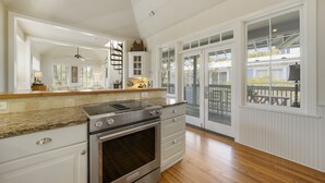 A kitchen with a built-in oven, a stove, and a countertop with a range hood. There is a large window with a view of the outside. - Updated in Seaside, Amazing Porches, Close to West Side Pool + 2 Adult Bikes! (Santa Rosa Beach)