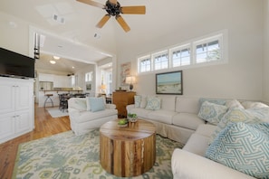 A spacious living room with a round coffee table, a white sofa, and a television.