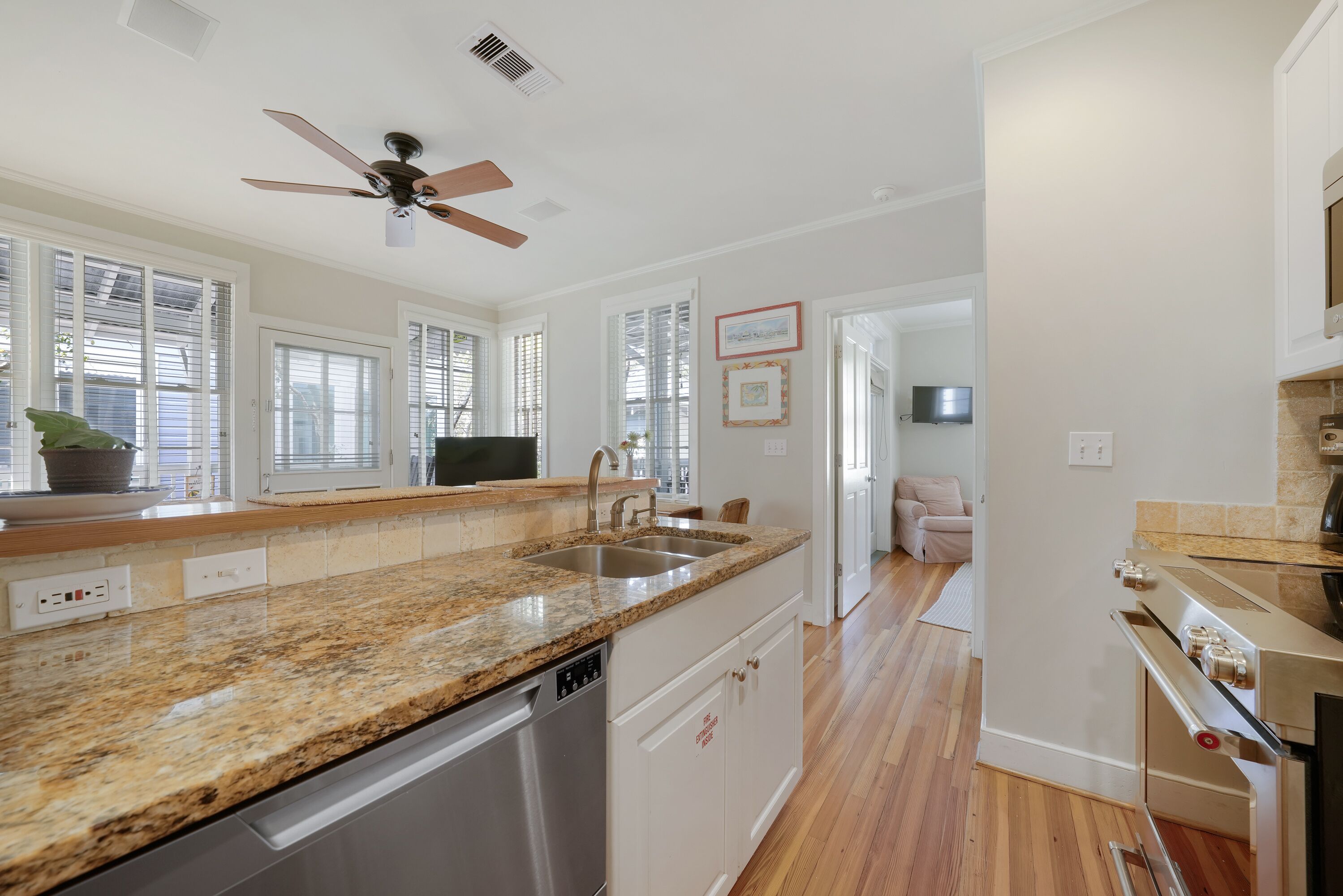 A modern kitchen with granite countertops, stainless steel appliances, and a ceiling fan.