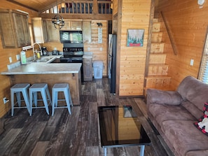 A cozy cabin interior with a kitchen, a dining area, and a living room.