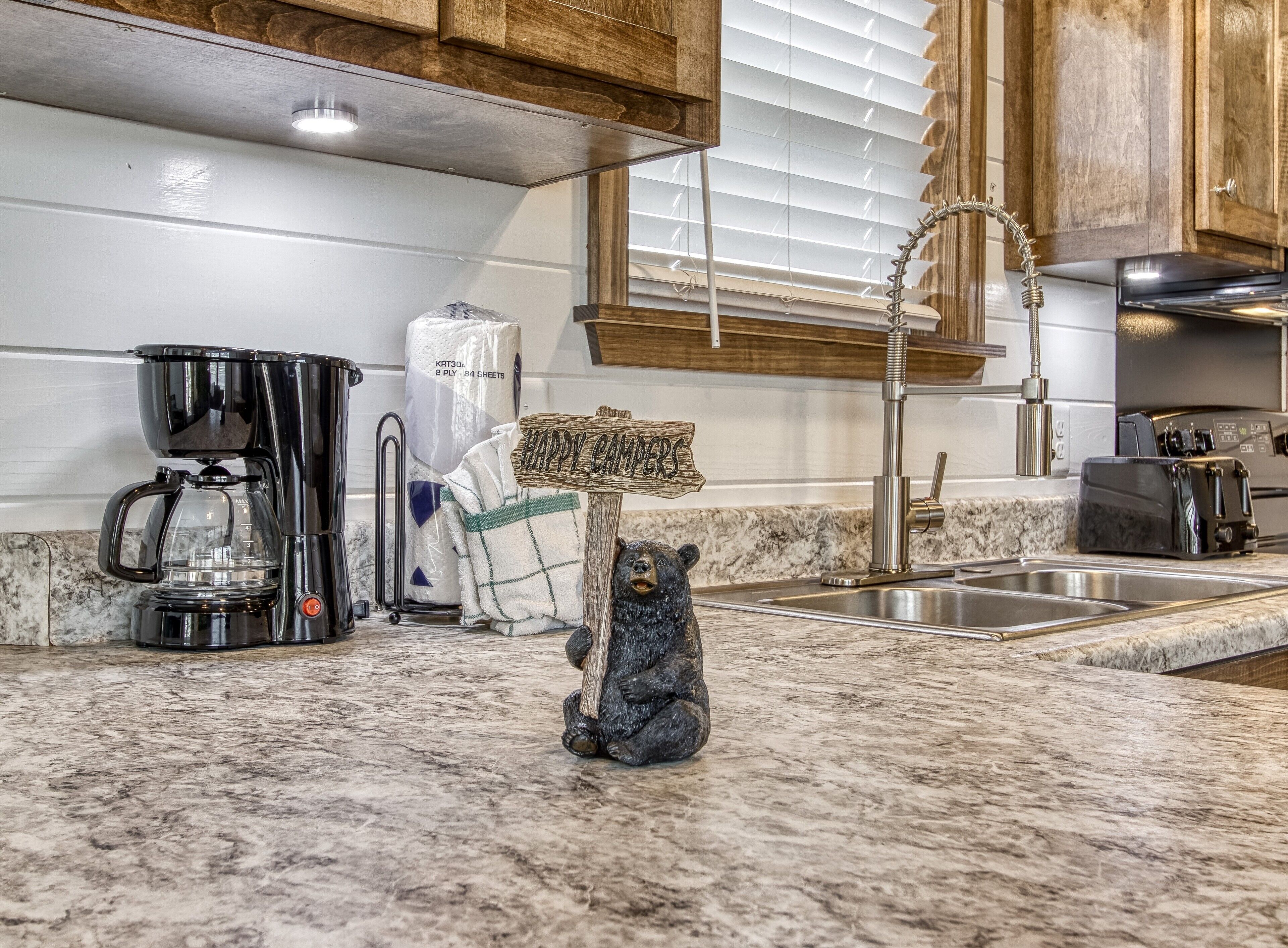 A kitchen with a coffee maker, a bear figurine, and a towel rack.