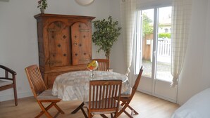 A dining area with a wooden table and chairs, a cabinet, and a plant. - CHARM AND TRANQUILITY ON THE ARCACHON BASIN (Andernos-les-Bains)