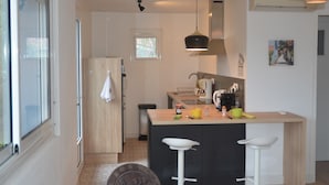 A compact kitchen with a central island, a small window, and a door. - CHARM AND TRANQUILITY ON THE ARCACHON BASIN (Andernos-les-Bains)