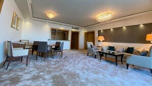 A spacious living area with a high ceiling, a chandelier, and a sofa set.