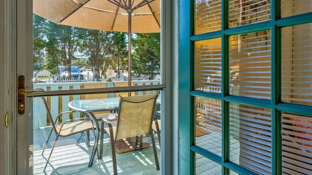 Vista desde el interior de una habitación con un ventanal grande, una puerta y una mesa con sillas.