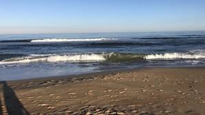 Una playa con olas y huellas en la arena.