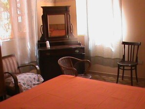 A hotel room with a bed, a wooden dresser, a chair, and a small table.