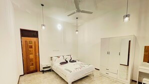 A bedroom with a bed, a wardrobe, a ceiling fan, and pendant lights.
